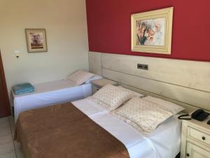 two beds in a room with red walls at Pousada Vila Verde in Porto Belo