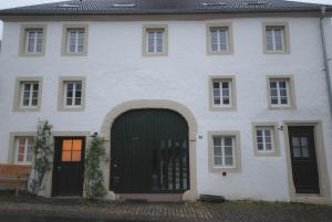 a large white house with a green door at Living-in-History: Historischer Charme und Design in Dudeldorf