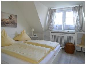 een witte slaapkamer met een bed en een raam bij Haus-Kim in Tinnum