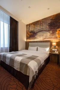a bedroom with a large bed with a painting on the wall at Sunflower Hotel Vnukovo in Moskovsky