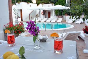 a table with drinks and a vase of flowers on it at Villa Romana Hotel & Spa in Minori