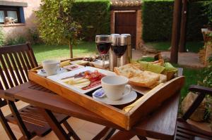una mesa de madera con una bandeja de comida y dos copas de vino en Casa Rural La Carretería, en Camañas