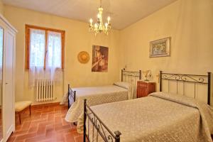sypialnia z 2 łóżkami i żyrandolem w obiekcie Vittoriana near San Gimignano by PosarelliVillas w mieście San Gimignano +37 zdjęć