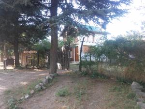 a tree in front of a house with a fence at Aire del Cerro in Capilla del Monte
