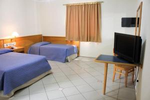 a hotel room with two beds and a flat screen tv at Jaguary Hotel Sumaré in Sumaré