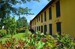 un edificio amarillo con persianas verdes. en Agriturismo Cascina Maiocca en Mediglia
