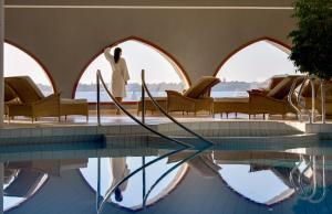 a man standing next to a swimming pool with chairs at Domaine de Rochevilaine in Billiers