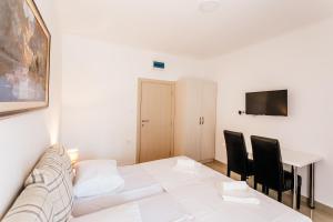 - une salle à manger blanche avec une table et des chaises blanches dans l'établissement Apartments Belani, à Herceg-Novi