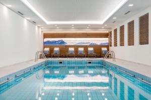 a pool in a hotel with chairs and an indoor swimming pool at Bauer Hotel und Restaurant in Feldkirchen