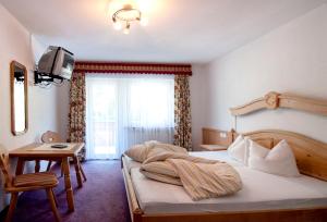 a bedroom with a bed and a table and a television at Garni-Appartement Collina in Samnaun +32 photos