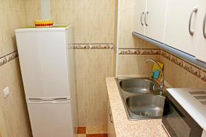una pequeña cocina con fregadero y nevera. en Apartamentos Tamarindos, en Benalmádena