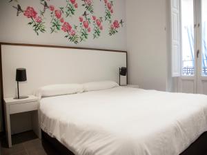瓦倫西亞的住宿－蘇荷朋友公寓，卧室配有白色的床铺,墙上挂着鲜花