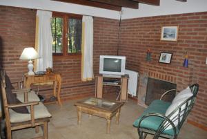 a living room with a tv and a fireplace at Cabañas Poetas del Bosque in Mar Azul