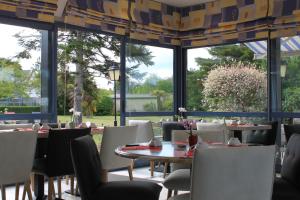 ein Esszimmer mit Tischen, Stühlen und großen Fenstern in der Unterkunft Hotel Des Bains in Lancieux