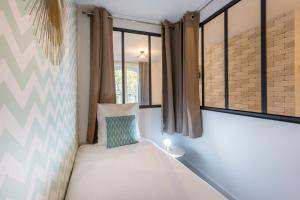 ein kleines Bett in einem Zimmer mit Fenstern in der Unterkunft Apartments WS St Germain - Quartier Latin in Paris