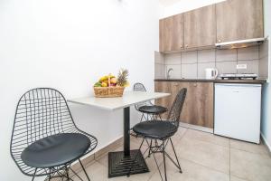eine Küche mit 2 Stühlen und einem Tisch mit Obst darauf in der Unterkunft Hillside Studios & Apartments in Faliraki