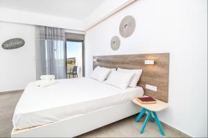 a white bedroom with a bed and a table at Hillside Studios & Apartments in Faliraki