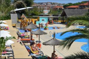 uma piscina com pessoas sentadas em cadeiras e guarda-sóis em Camping Sènia Tucan em Lloret de Mar