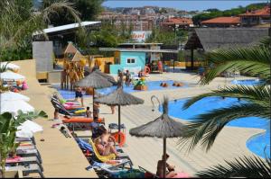 a pool with people sitting on chairs and umbrellas at Camping Sènia Tucan in Lloret de Mar