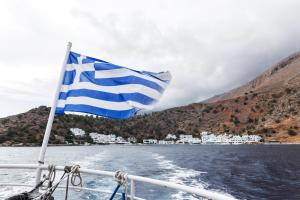 
a white and blue flag flying over a body of water at Daskalogiannis Hotel in Loutro
