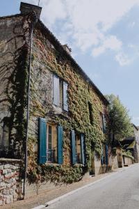 an ivy covered building with blue shutters and windows at La Maison Bleue in Villeréal