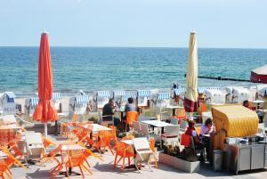 eine Gruppe von Menschen, die an Tischen in der Nähe des Ozeans sitzen in der Unterkunft Ostseewind - in der Strandstrasse-führt zur Seebrücke in Kühlungsborn