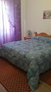 a bedroom with a bed with a blue comforter at SA SPENDULA B&B in Villacidro