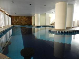 a swimming pool in a hotel with columns at Príncipe Hotel in Poços de Caldas