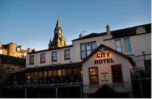 a large white building with a lit up city hotel at The City Hotel in Dunfermline