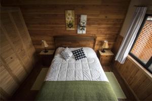 1 dormitorio con 1 cama en una cabaña de madera en Cabañas Entre Verdes, en Frutillar