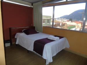Un dormitorio con una cama con una ventana grande. en El Centro Hotel, en Quetzaltenango