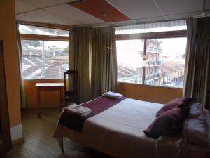 Un dormitorio con una cama y una ventana grande en El Centro Hotel, en Quetzaltenango