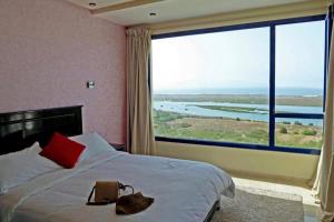 a bedroom with a large bed with a large window at Le temps perdu in Oualidia