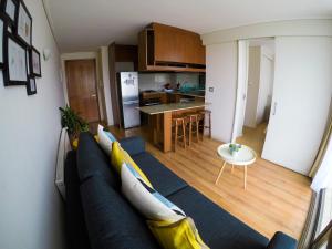 a living room with a blue couch and a kitchen at Marina Poniente Apartment in Viña del Mar