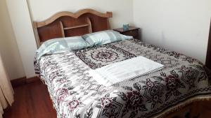 a bed with a black and white comforter on it at Hostal Algas Del Titicaca in Copacabana