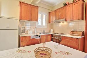 eine Küche mit Holzschränken, einem Tisch und einem Kühlschrank in der Unterkunft Mattheos House in Kalámi