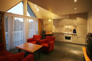 a living room with red chairs and a table and a kitchen at Landhaus Mühlenberg in Willingen