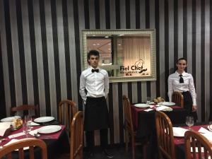 Zwei Männer stehen in einem Restaurant mit Tischen. in der Unterkunft Fiel Chef Alojamento Local in Valongo