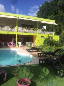 une maison jaune avec une piscine en face de celle-ci dans l'établissement Location tropical, à Sainte-Anne
