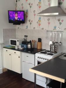a kitchen with a stove and a tv on the wall at No 16 The Hub Abercrave in Swansea