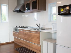una cocina con fregadero y refrigerador en The Pool Resort Villa ICHIGOICHIE, en Onna