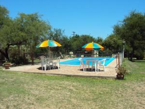 a table and chairs and umbrellas next to a pool at Pasos Cortos Cabañas Nono in Nono