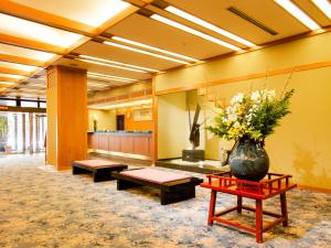 un vestíbulo con bancos y un jarrón de flores sobre una mesa en Hoseikan, en Matsue