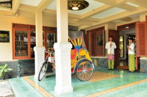 un rickshaw estacionado frente a un edificio en Balai Melayu Hotel, en Yogyakarta