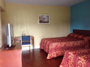 a hotel room with two beds and a flat screen tv at Ole English Inn in Tuscaloosa