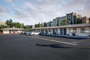 un estacionamiento con autos estacionados frente a un edificio en Harbor Motel, en Anaheim