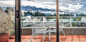 a table and chairs on a balcony with a view of mountains at The Lofts Apartments in Queenstown