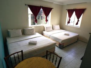 two beds in a room with two windows at Abell Residence in Kuching