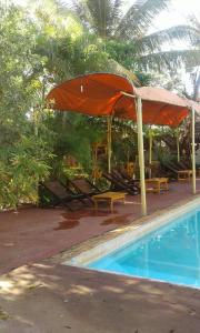 a pool with an umbrella and chairs and a table at Le Village Diego in Diego Suarez