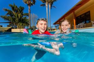 two young men are playing in a swimming pool at BIG4 Whiters Holiday Village in Lakes Entrance